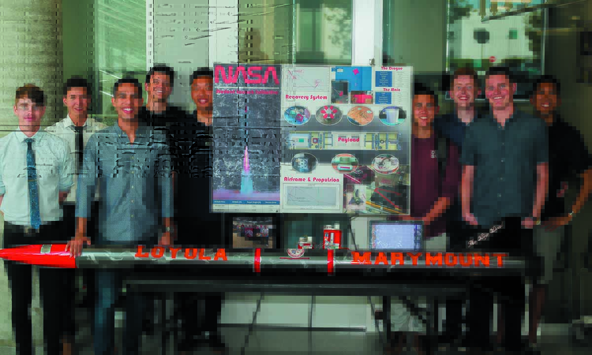 Rocket team standing in front of poster and rocket